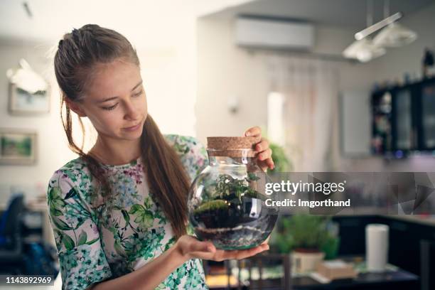 chica adolescente sosteniendo un jardín de botellas - terrarium fotografías e imágenes de stock