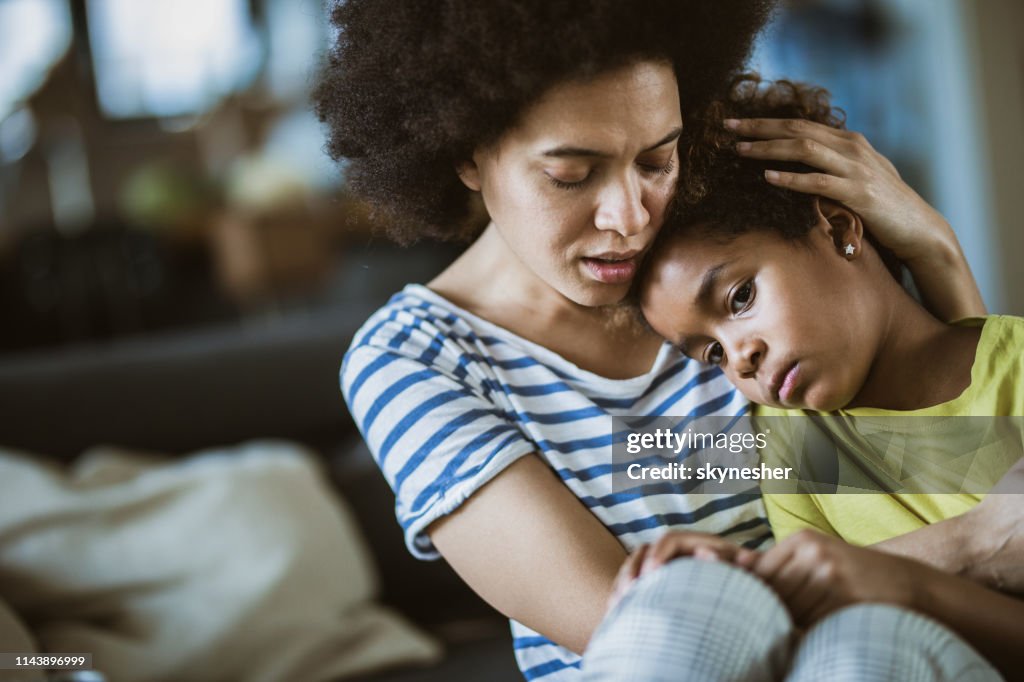 Junge schwarze Mutter kümmert sich zu Hause um ihre traurige kleine Tochter
