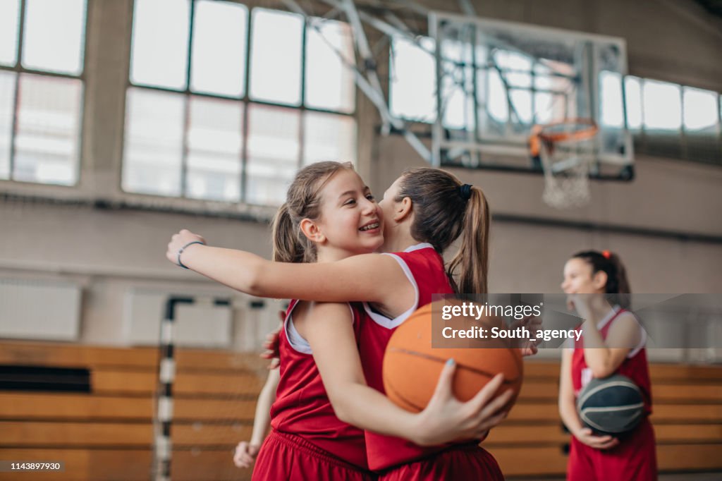 Mädchen Basketballspieler umarmen sich nach Spiel auf dem Platz