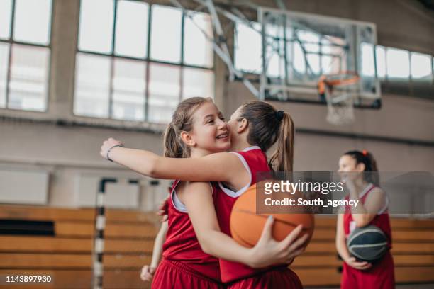mädchen basketballspieler umarmen sich nach spiel auf dem platz - sportbegriff stock-fotos und bilder