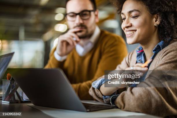 happy black businesswoman and her male colleague using laptop in the office. - email marketing stock pictures, royalty-free photos & images