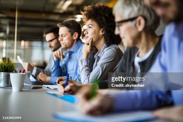 pensive african american businesswoman among her colleagues in the office. - group people thinking stock pictures, royalty-free photos & images