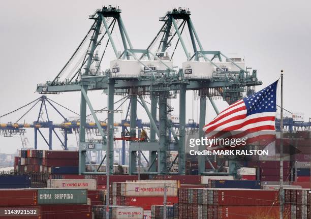 Chinese shipping containers are stored beside a US flag after they were unloaded at the Port of Los Angeles in Long Beach, California on May 14,...