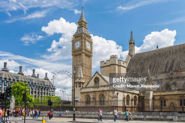 mensen lopen tijdens een zomerse dag naast de houses of parliament en de big ben in de stad westminster, londen, engeland, uk. - parliament square stockfoto's en -beelden