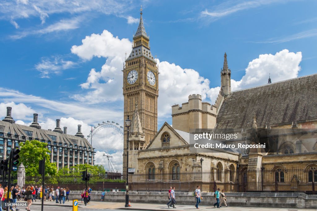 People walking during a summer day next to the Houses of Parliament and the Big Ben at the City of Westminster, London, England, UK.