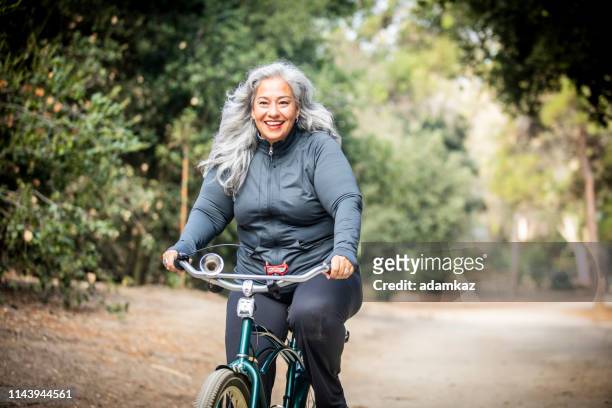 senior mexicaanse vrouw rijden fiets - overweight stockfoto's en -beelden