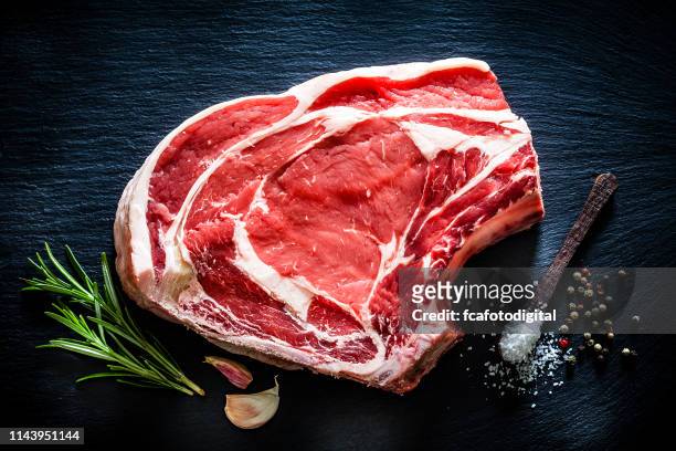 raw rib steak shot from above on black background - beef stock pictures, royalty-free photos & images