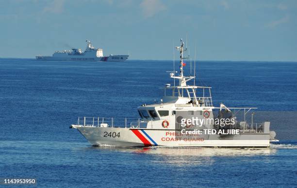 This photo taken on May 14 a Philippine coast guard ship sails past a Chinese coastguard ship during an joint search and rescue exercise between...