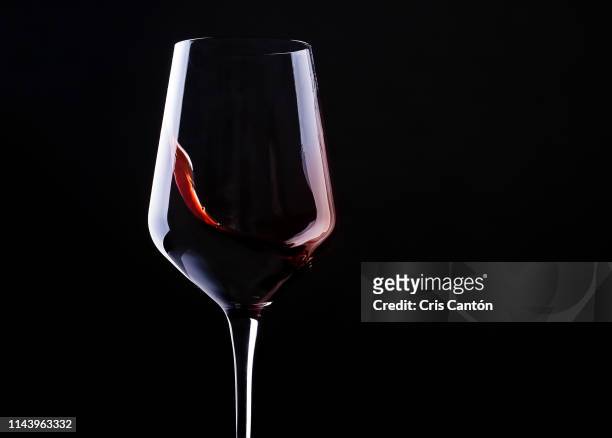 red wine swirling into glass - red wine stock-fotos und bilder