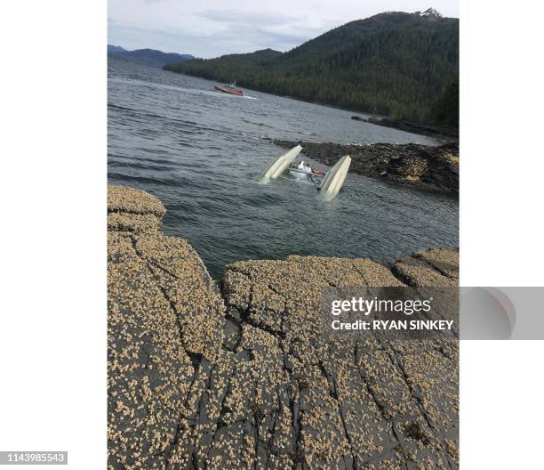 In this image courtesy of Ryan Sinkey and released by the US Coast Guard , a floatplane lies upside down after a mid-air collision with another plane...