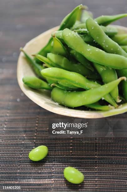 bowl of edamame beans on bamboo mat - edamame stock pictures, royalty-free photos & images