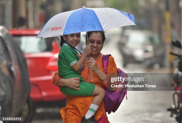 Woman and child shelter under an umbrella amid light early morning rain and a thunder storm, on May 15, 2019 in New Delhi, India. Parts of Delhi-NCR...