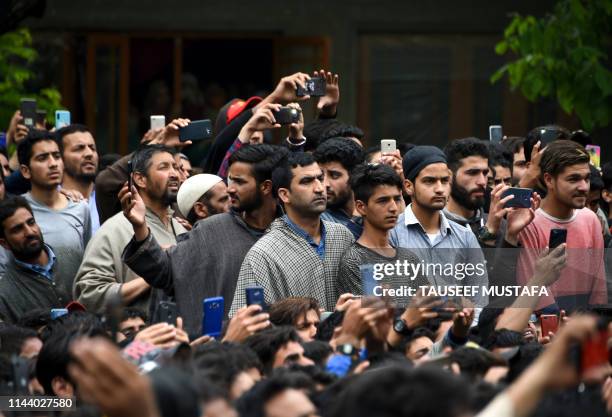 Kashmiri villagers look on and take photos during the funeral procession of a militant commander of the Jaish-e-Mohammed, Naseer Pandith, at Pulwama,...