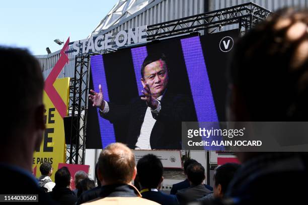 People wacth on a giant screen, set outside the venue at the Paris Expo of Portes de Versaille, the Chinese Alibaba group CEO Jack Ma speaking during...