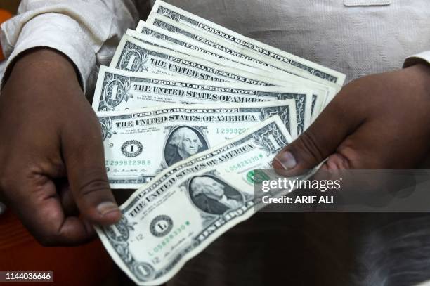 Pakistani man counts US dollars at the currency exchange place in Lahore on May 16, 2019. Pakistan's rupee dropped to an all-time low of 146.5 to the...