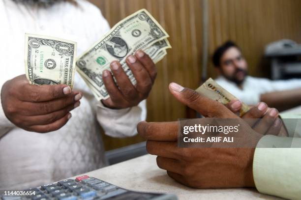 Pakistani man counts US dollars at the currency exchange place in Lahore on May 16, 2019. Pakistan's rupee dropped to an all-time low of 146.5 to the...