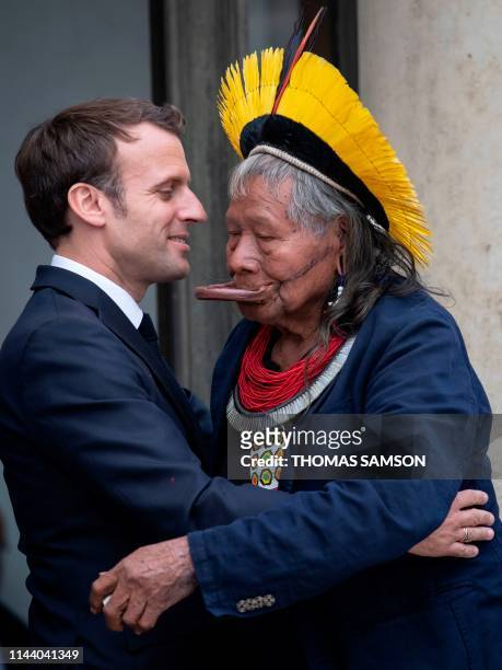 Brazil's legendary indigenous chief Raoni Metuktire embraces French President Emmanuel Macron after their meeting at the Elysee Palace on May 16,...