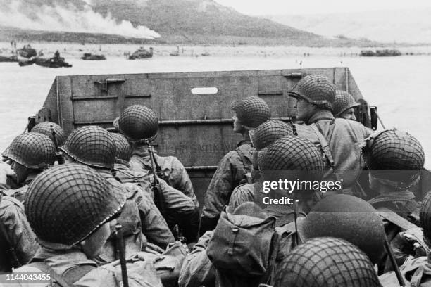 American assault troops in a landing craft huddle behind the shield 06 June 1944 approaching Utah Beach while Allied forces are storming the Normandy...