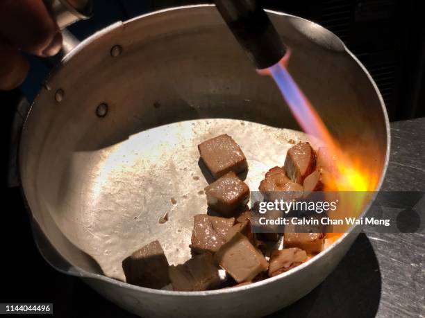 cooking pork cubes with culinary torch - たいまつ ストックフォトと画像