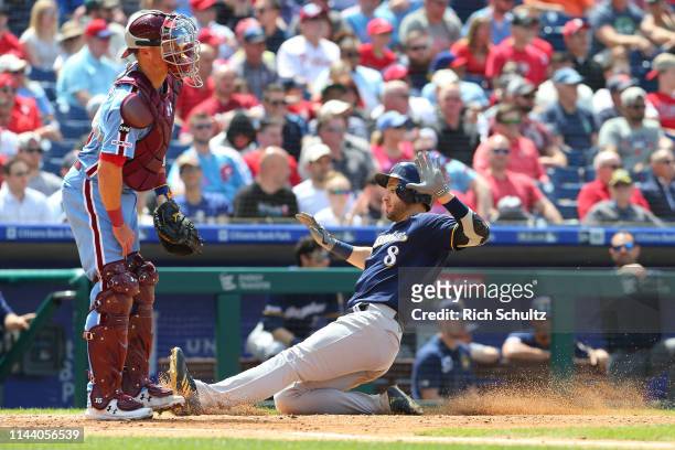 Ryan Braun of the Milwaukee Brewers scores on a sacrifice fly by Yasmani Grandal as catcher Andrew Knapp of the Philadelphia Phillies waits for the...
