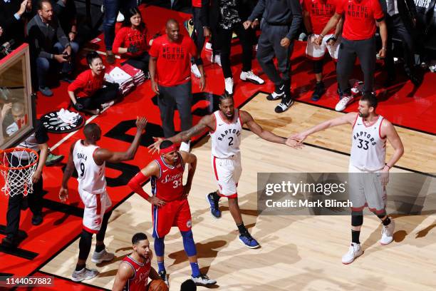 Kawhi Leonard hi-fives Serge Ibaka and Marc Gasol of the Toronto Raptors during Game Seven of the Eastern Conference Semifinals of the 2019 NBA...