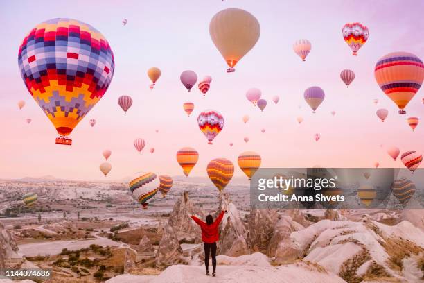 young woman on a background of flying balloons at sunrise in cappadocia - cappadocia hot air balloon stock-fotos und bilder