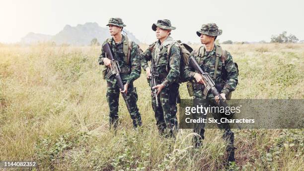 asian army soldiers with guns during the military operation in the field, war concept - military rescue stock pictures, royalty-free photos & images