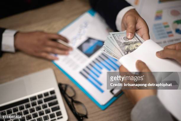 corruption concept,businessman giving bribe money  to partner in a corruption scam with black  tone,corruption - bribery stock pictures, royalty-free photos & images
