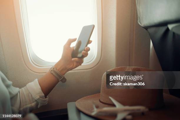 female passenger use smartphone near window seat in airplane after take off - airplane phone stock pictures, royalty-free photos & images