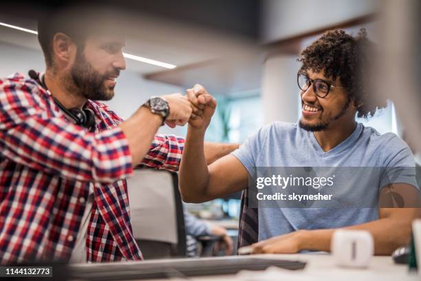 programadores de computadoras felices dándonos el golpe de puño en la oficina. - fist bump fotografías e imágenes de stock