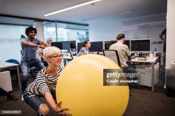 fröhliche programmiererin, die mit fitnessball im büro trainiert. - exercise ball stock-fotos und bilder