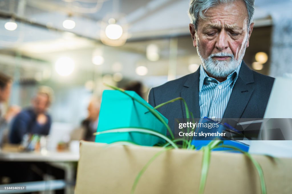 Retired senior businessman leaving the office with his belongings.