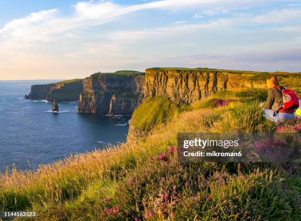 young woman at cliffs of moher, ireland - cliffs of moher stock-fotos und bilder