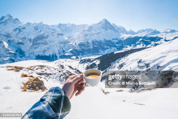 personal perspective of human hand holding a cup of coffee in the swiss alps - mountains pov stock-fotos und bilder