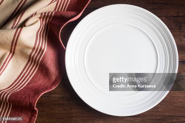 empty white plate with a napkin on an old wooden brown background, top view. image with copy space. kitchen table with a towel and a plate - top view with copy space. - checkered table cloth stock pictures, royalty-free photos & images