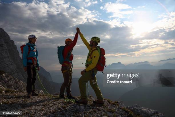 drei bergsteiger feiern auf der spitze - bergsteiger gipfel stock-fotos und bilder