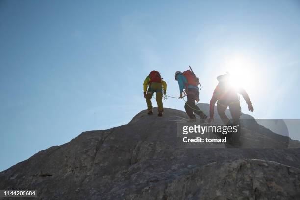 group of mountaineers walking on the edge - three people silhouette stock pictures, royalty-free photos & images