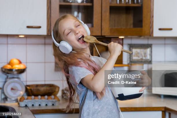 little girl enjoying music while preparing food in kitchen - singing for kids stock pictures, royalty-free photos & images