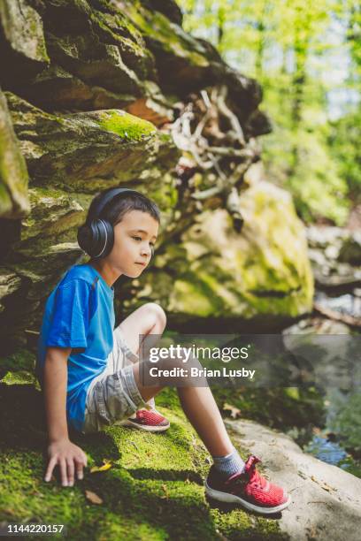 little boy listening to headphones outdoors - boy headphones imagens e fotografias de stock