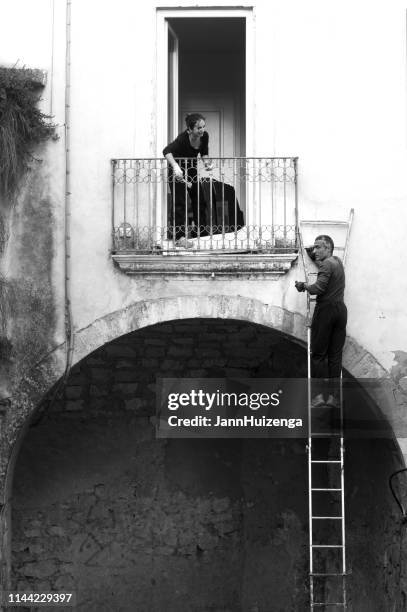 ragusa, sicily, italy: man on ladder, woman on balcony - ragusa sicily stock pictures, royalty-free photos & images