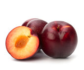 Three red plums - one cut in half and pitted - on white