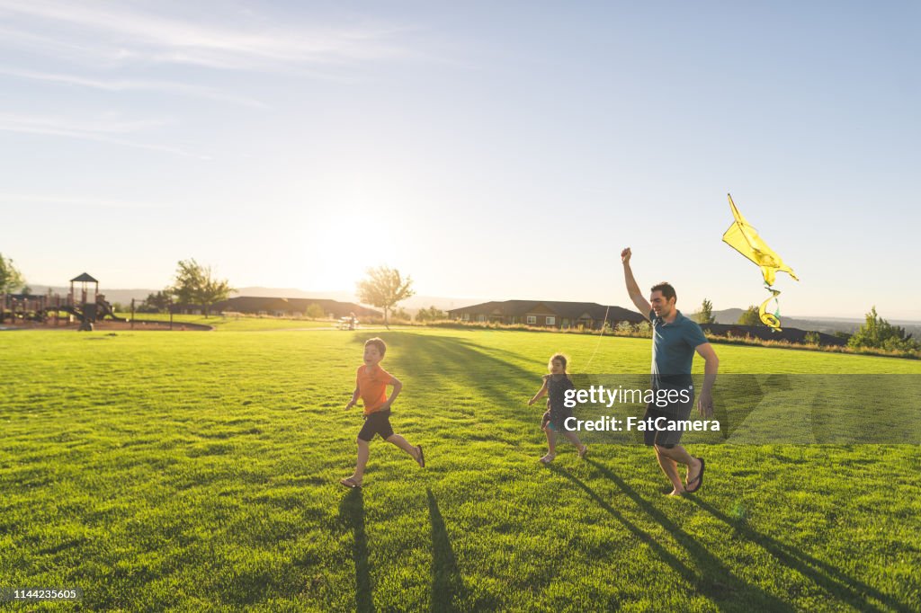 Dad flying kites with his kids at the park