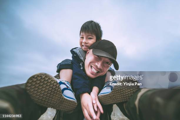 low angle view selfie portrait of the son sitting on his father's shoulder, shanghai, china - wide angle imagens e fotografias de stock