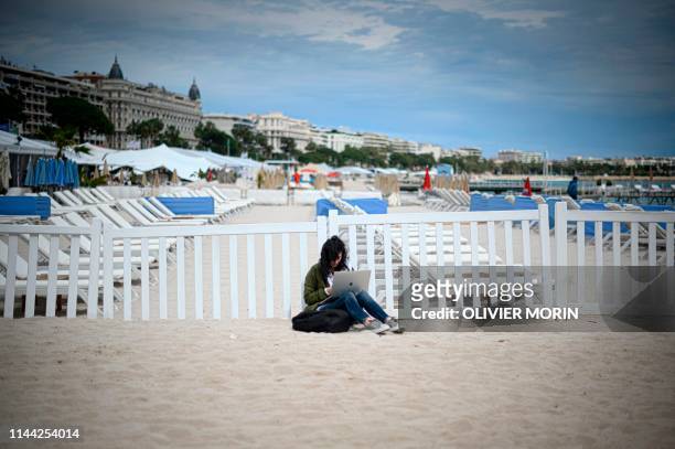 Woman uses a laptop as she sits on a beach during the 72nd edition of the Cannes Film Festival in Cannes, southern France, on May 17, 2019.