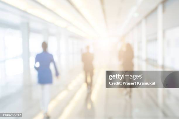 blurred background of businesspeople standing in the corridor of an business center - backgrounds people stock-fotos und bilder