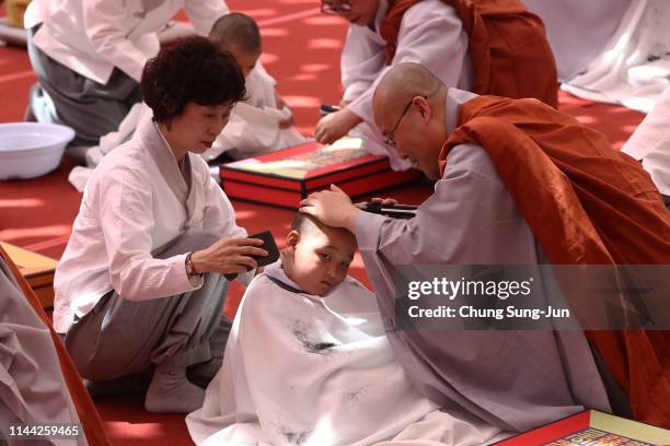 Child gets his head shaved by a Buddhist monk during the 'Children Becoming Buddhist Monks' ceremony forthcoming buddha's birthday at a Jogye temple...