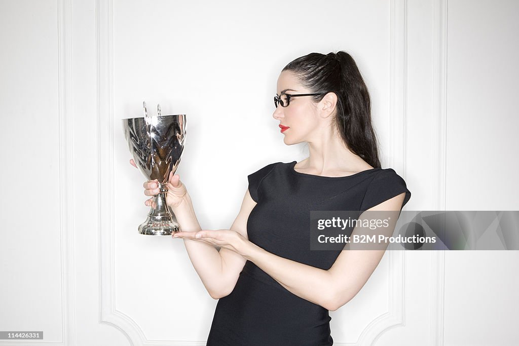 Young woman holding up trophy