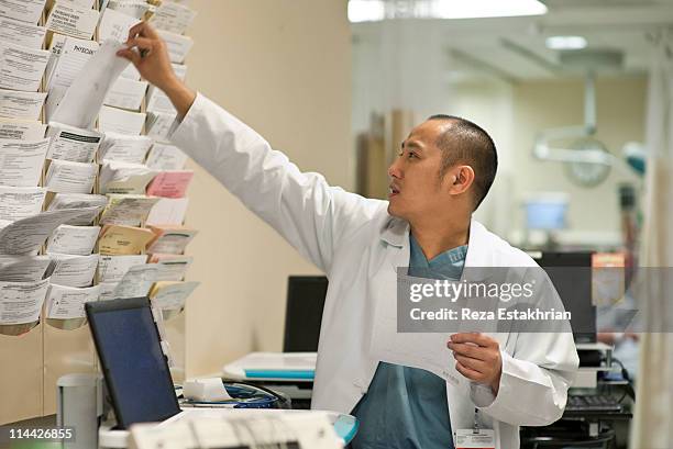 doctor selects information for patient - busy doctor stock pictures, royalty-free photos & images