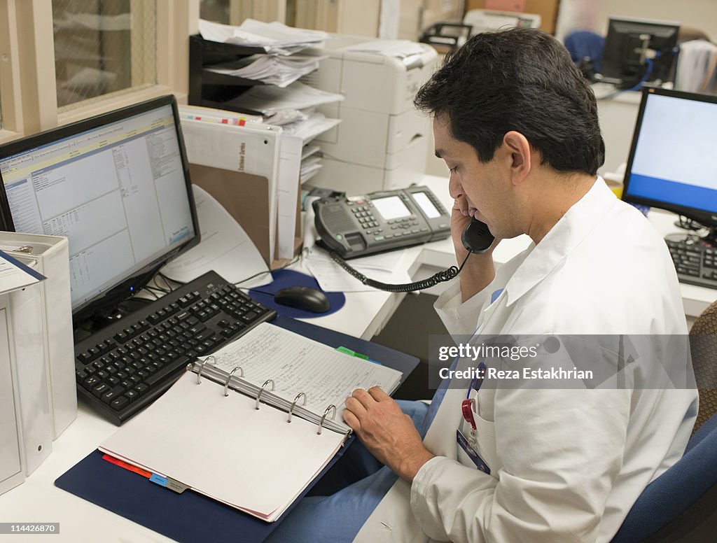 Doctor talks on phone while checking his notes