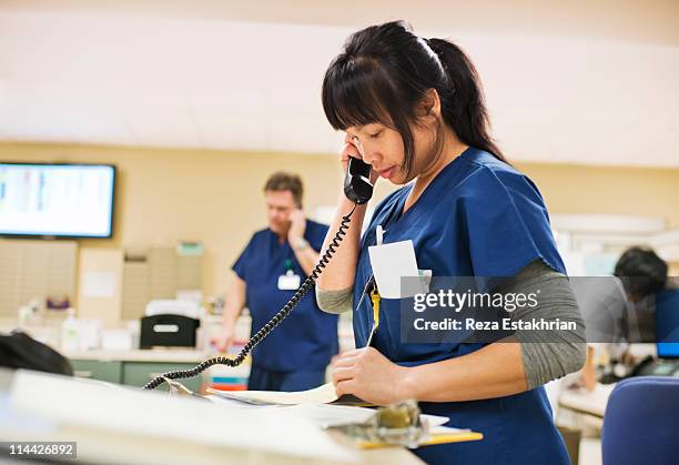 nurse checks notes while talking on phone - nurse working stock pictures, royalty-free photos & images